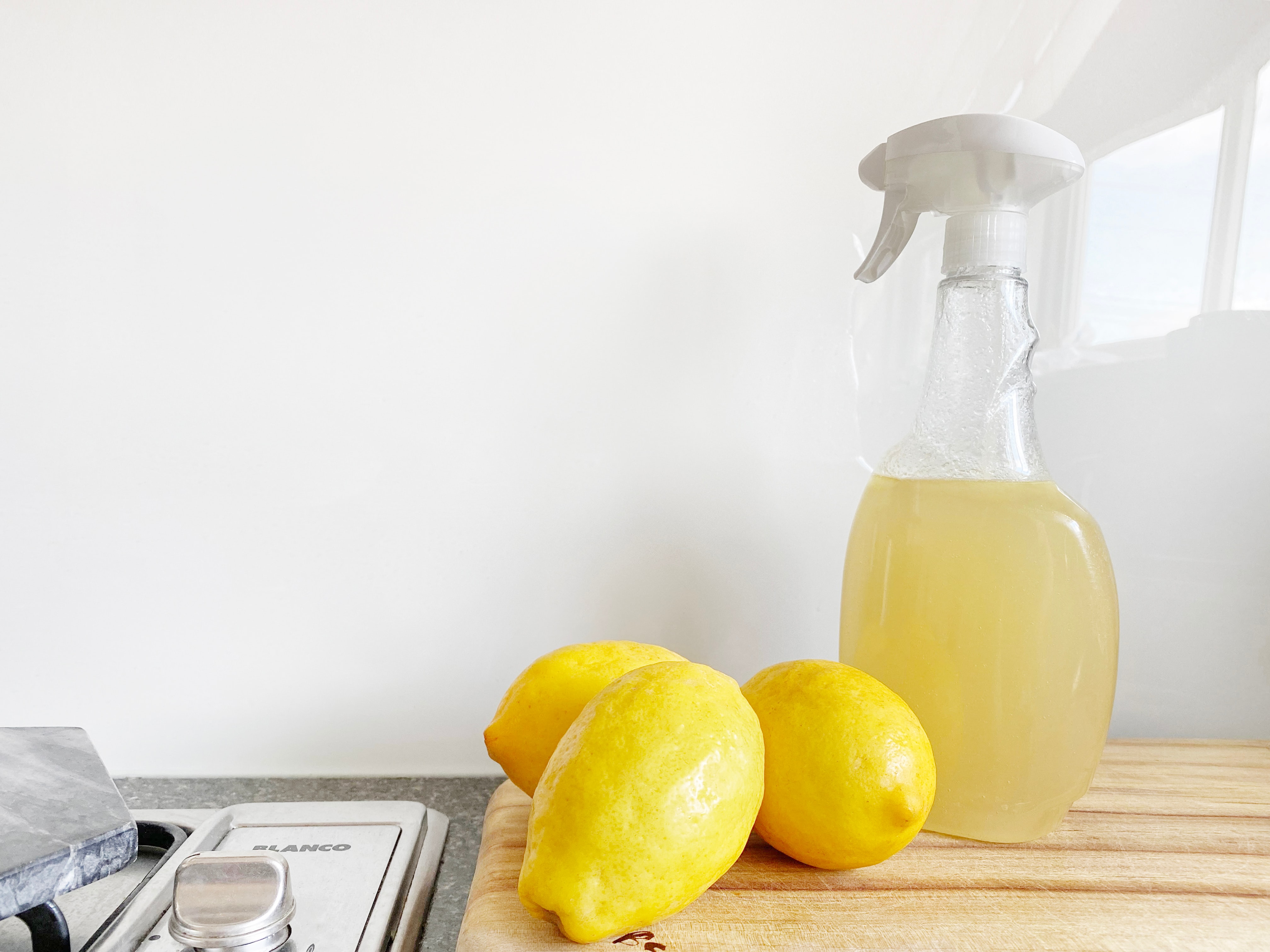 Spray bottle of lemon natural kitchen cleaner next to stovetop ready for cleaning